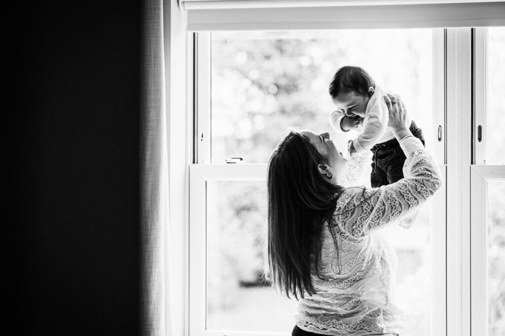 Mum and baby play in the window light at home