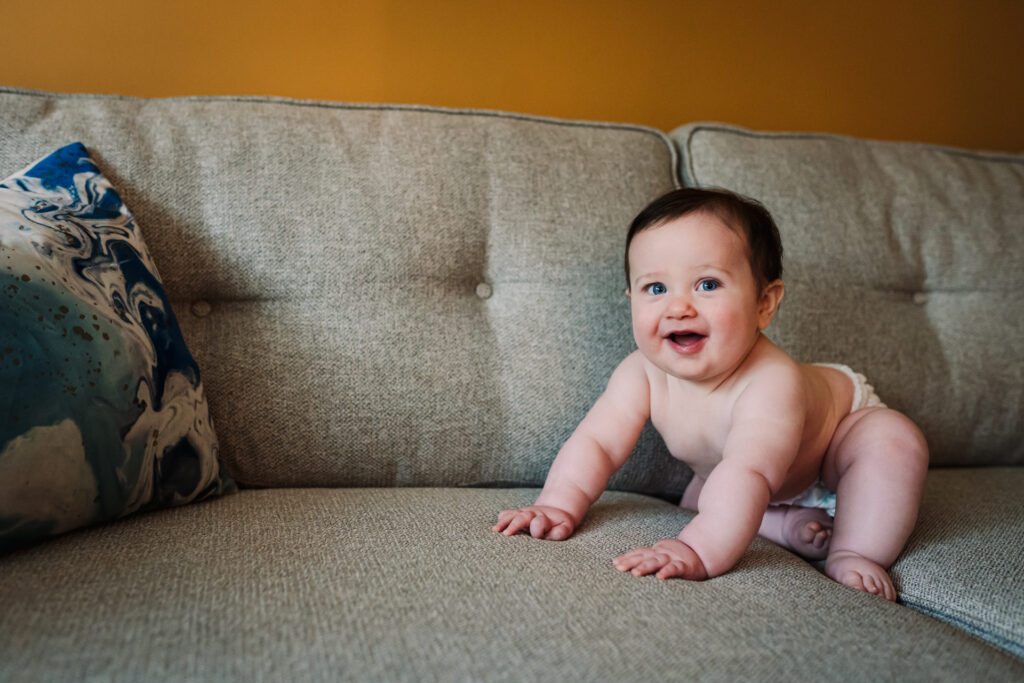 Chubby baby smiles on the sofa in his Hertfordshire home