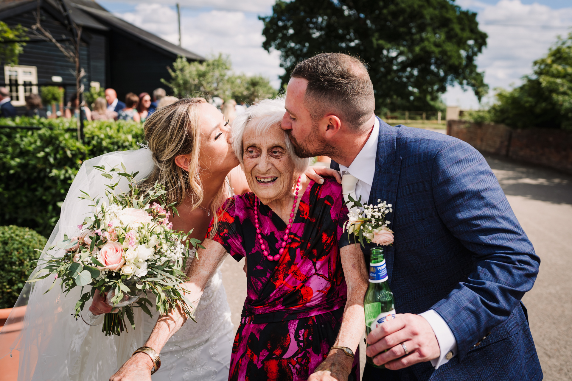 Bride and groom kiss the grooms grandmother on both cheeks as she leaves the Milling Barn wedding reception