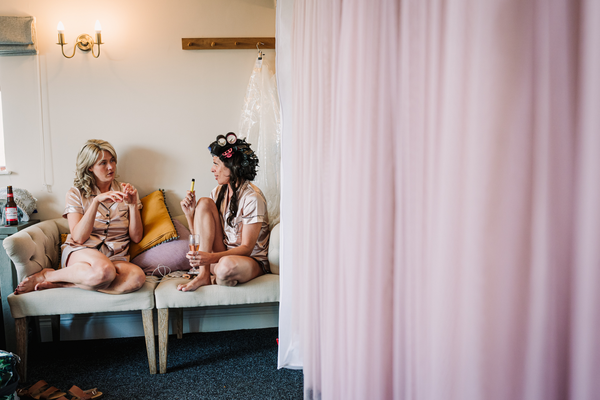 Bridesmaids chat whilst getting ready for the wedding at Milling Barn in Hertfordshire
