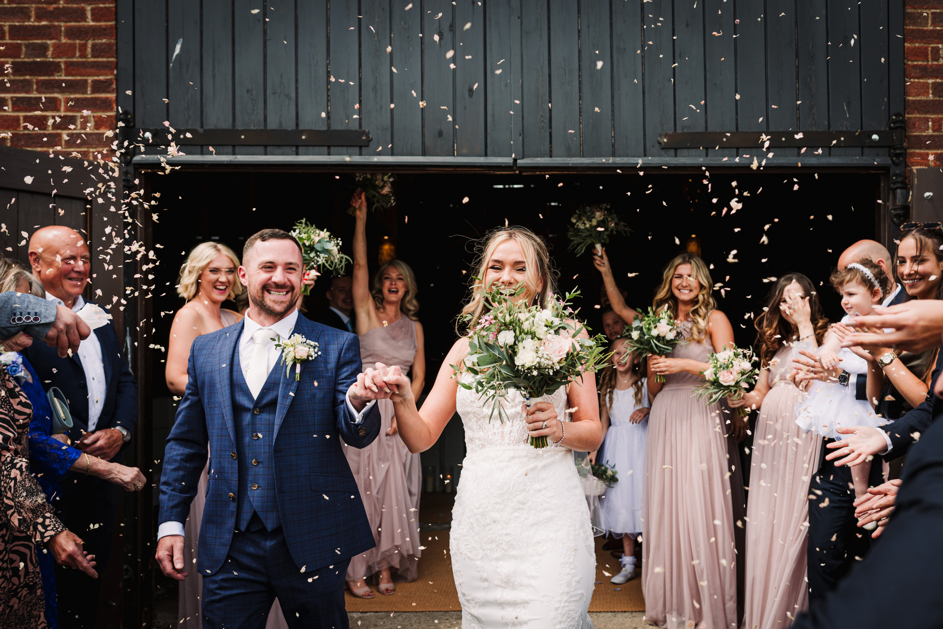 Bride and groom laugh amongst confetti after the Milling Barn wedding ceremony