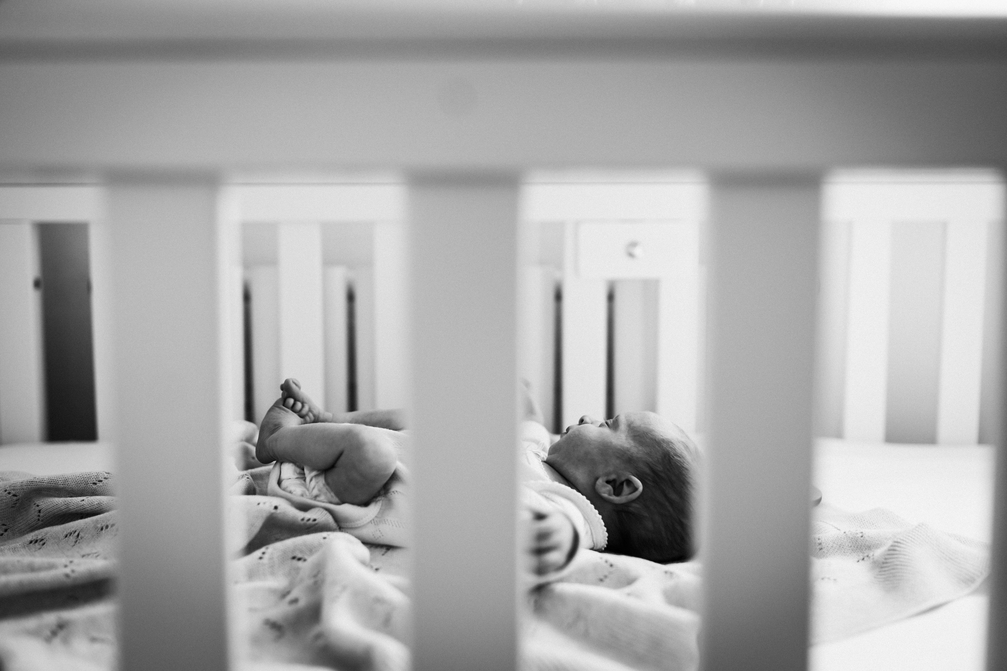 photographed through the slats of her cot, newborn sleeps peacefully
