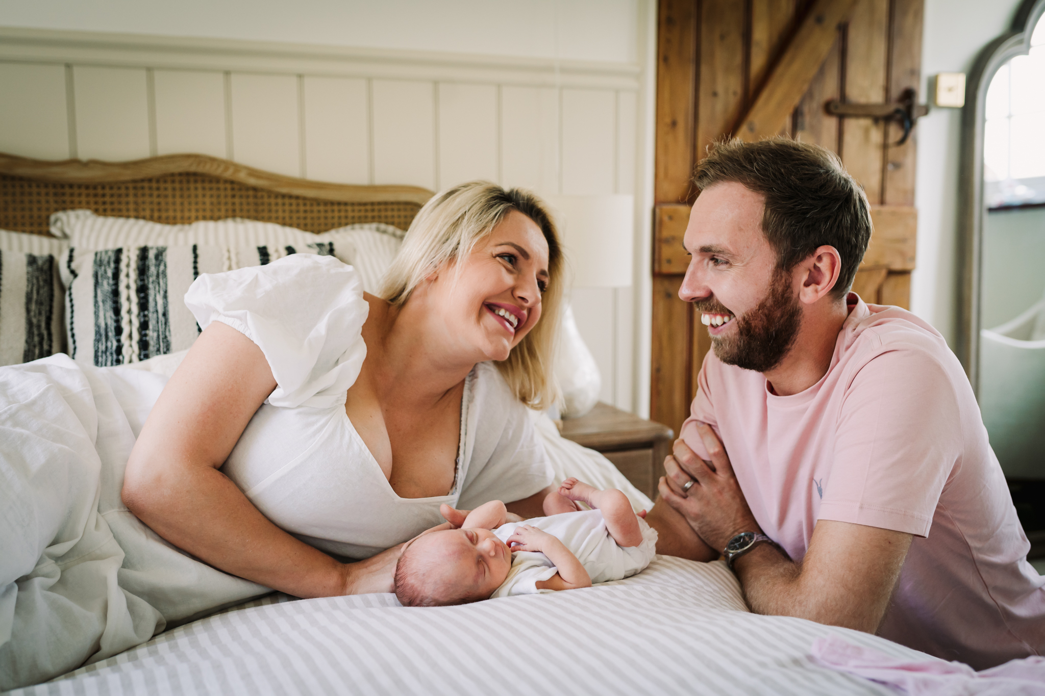 new parents smile at each other as they hold their newborn