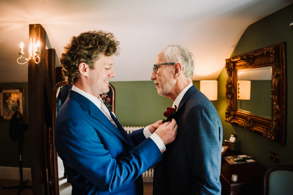 groom helps father of the bride attach his wedding day button hole