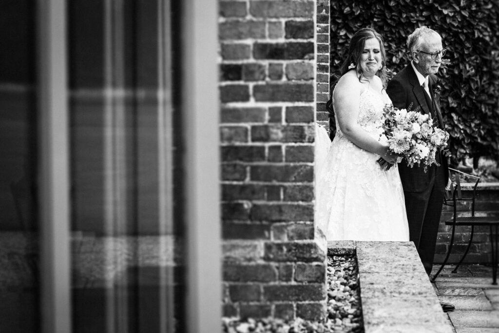 bride holds back emotion as she walks down the aisle at Offley Place